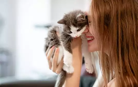Woman pulling kitten towards her face